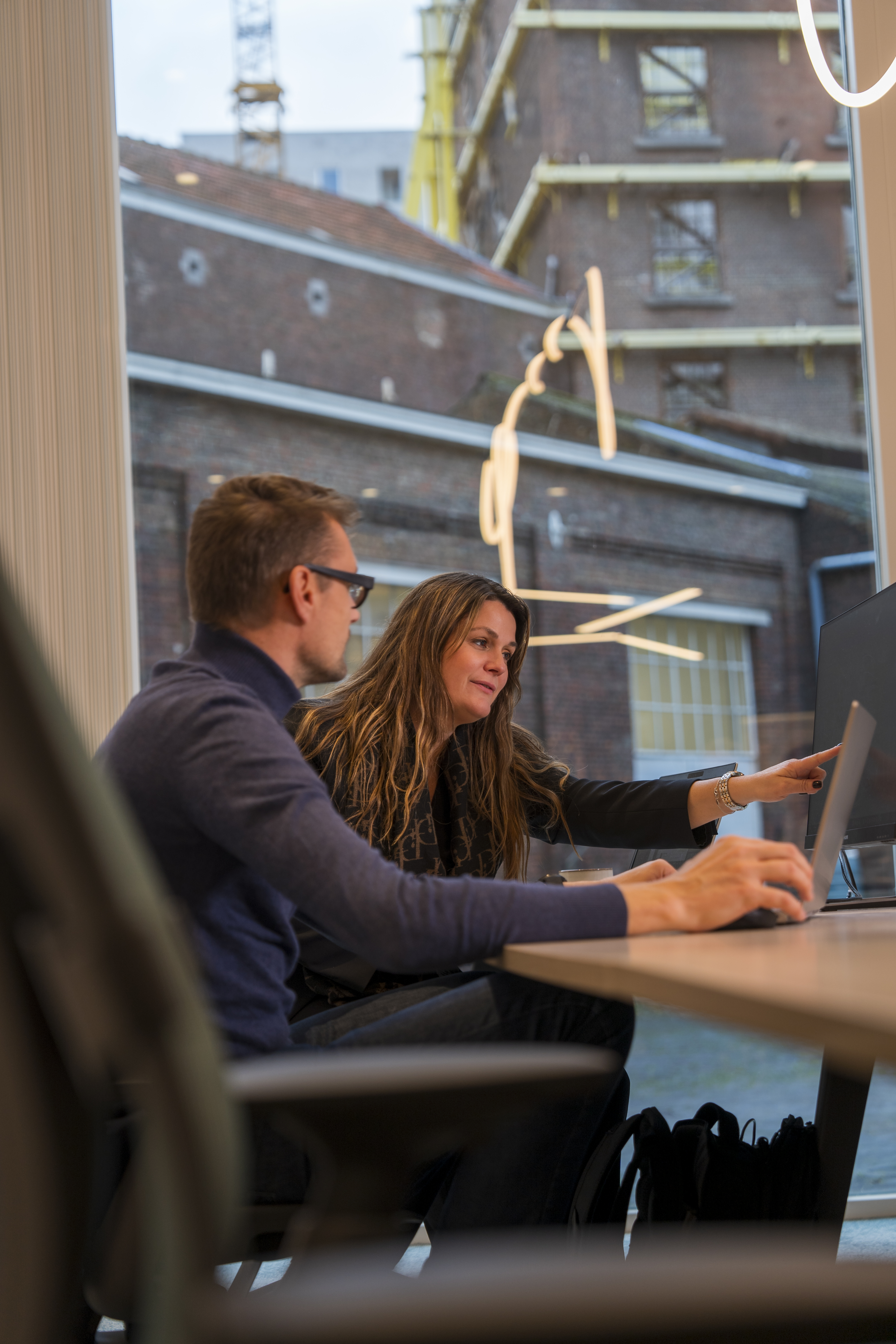 Twee workplace consultants bekijken een kantoorconcept op een computer.